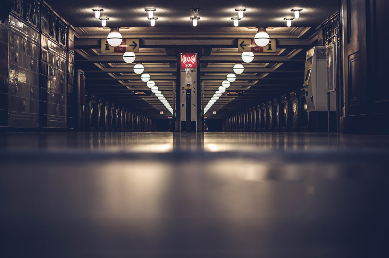 services-01 Dark and moody view of an empty underground subway station with modern lighting and steel architecture.